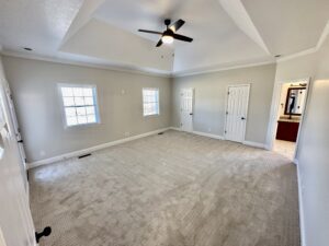 A large room with two windows and a ceiling fan.