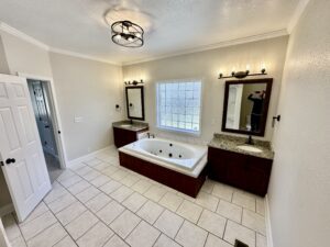 A large bathroom with two sinks and a tub.