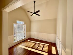 A room with a ceiling fan and wooden floors