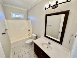 A bathroom with white tile and a large mirror.