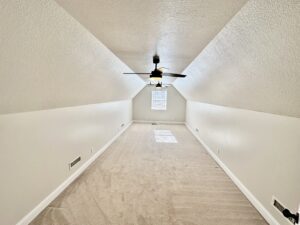 A ceiling fan in the middle of an empty room.