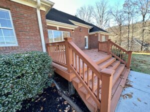 A wooden deck with steps and stairs leading to the front door.