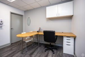 A desk with chair and computer in an office.