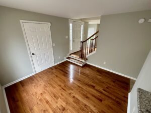 A room with hardwood floors and stairs leading to the second floor.