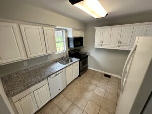 A kitchen with white cabinets and black appliances.