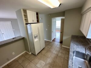 A kitchen with white appliances and tile floors.