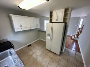 A kitchen with white cabinets and tile floors.