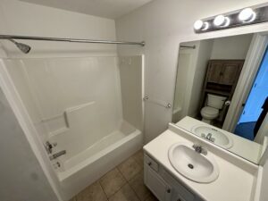 A bathroom with white fixtures and tile floors.