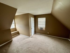 A room with tan walls and beige carpet.