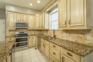 A kitchen with white cabinets and granite counter tops.