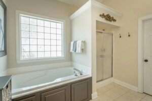 A bathroom with a tub, shower and window.