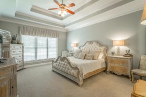 A bedroom with a bed, two nightstands and a ceiling fan.