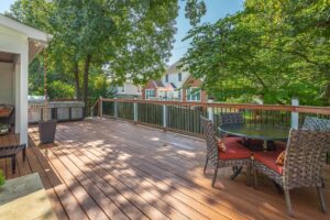 A deck with a grill and table in the middle of it.