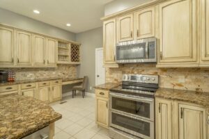 A kitchen with white cabinets and granite counter tops.