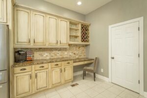 A kitchen with white cabinets and tile floors.