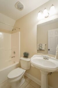 A bathroom with white fixtures and beige walls.