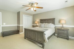 A bedroom with a bed, two nightstands and a ceiling fan.