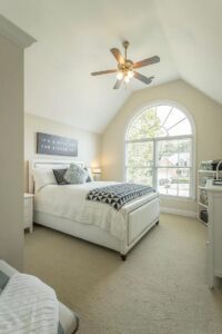 A bedroom with a bed, dresser and window.