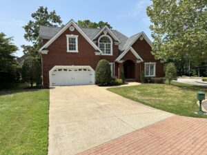 A large brick house with two cars parked in front of it.