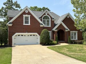 A large brick house with two cars parked in front of it.