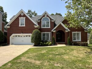 A large brick house with a driveway and lawn.