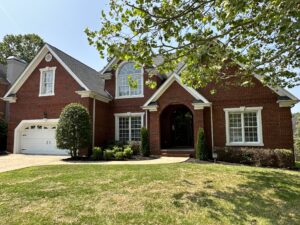 A large brick house with a tree in front of it.