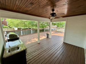 A covered patio with an outdoor grill and ceiling fan.