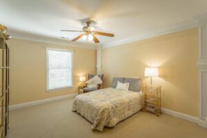 A bedroom with a bed, chair and window.