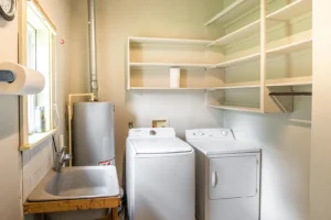 A room with two white appliances and shelves.