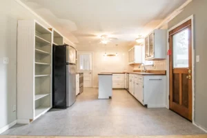 A kitchen with white cabinets and a refrigerator.