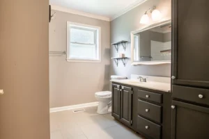 A bathroom with a sink, toilet and mirror.