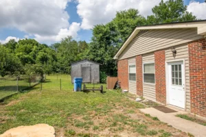 A house with a trash can in the yard.