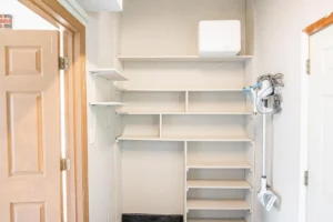 A white shelf in the corner of a room.