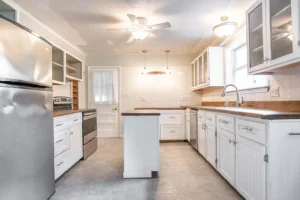 A kitchen with white cabinets and tile floors.