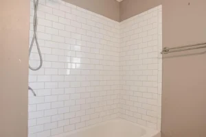 A white tiled bathroom with a shower and tub.