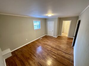 A room with hard wood floors and a door open.