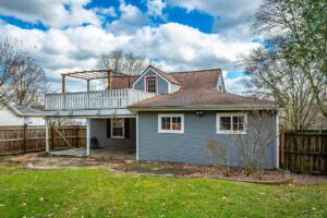 A house with a deck and lawn in the back.