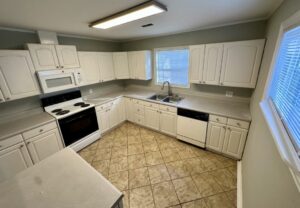 A kitchen with white cabinets and tile floors.