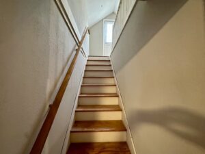 A wooden staircase with white walls and wood treads.