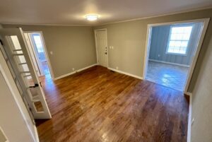 A room with hard wood floors and a door open.