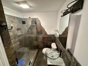 A bathroom with a glass shower door and tiled walls.