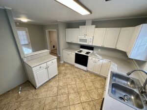 A kitchen with white cabinets and tile floors.