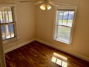 A room with hard wood floors and a ceiling fan.