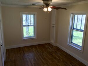 A room with two windows and a ceiling fan.