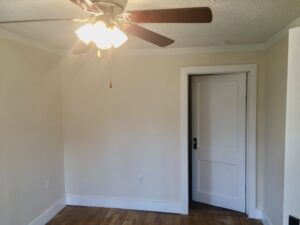 A room with a ceiling fan and wooden floors.