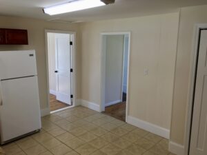 A kitchen with white walls and tile floors.