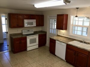 A kitchen with brown cabinets and white appliances.