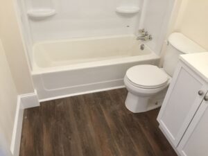 A bathroom with wood flooring and white fixtures.