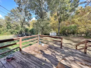 A wooden porch with a car parked in front and trees all around