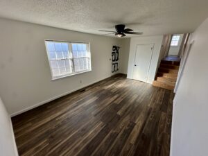 an empty room with ceiling fan and windows